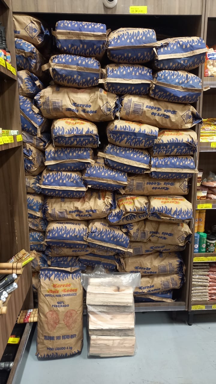 Carvão Dois Leões em prateleira de mercado junto com lenha